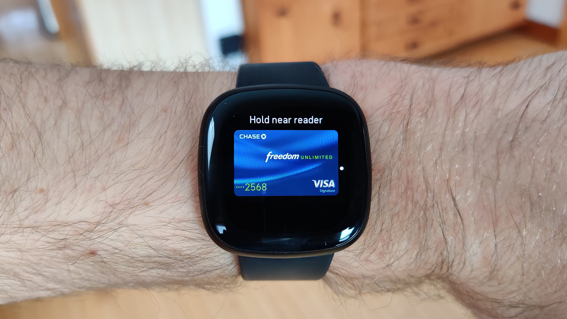 用户手臂上的fitbit Versa 3在Fitbit Pay上显示他的追逐卡。
