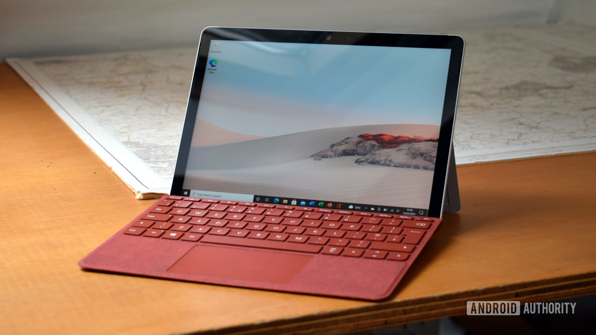 Microsoft Surface GO 2评论，带有罂粟红色表面类型盖子坐在桌子上。