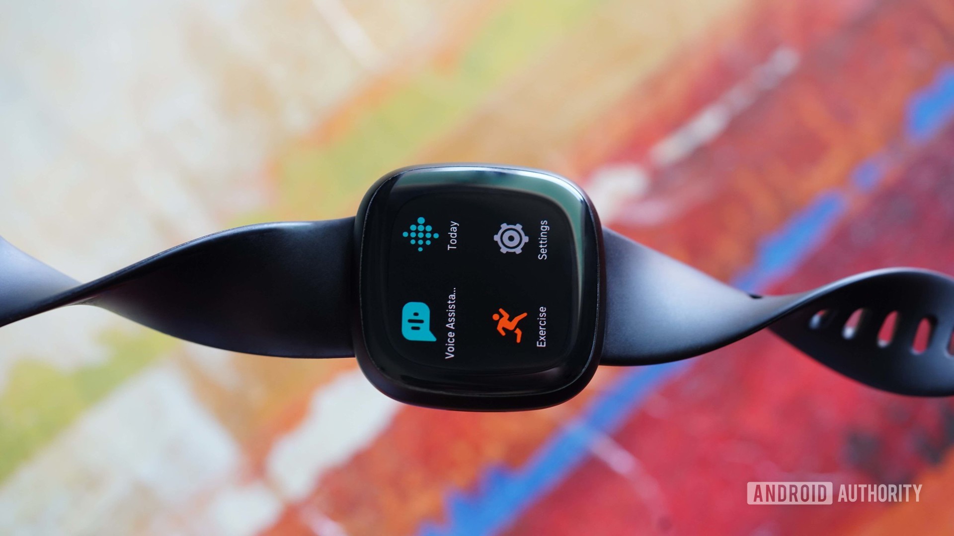 Fitbit Versa 3休息在抽象，彩色背景。